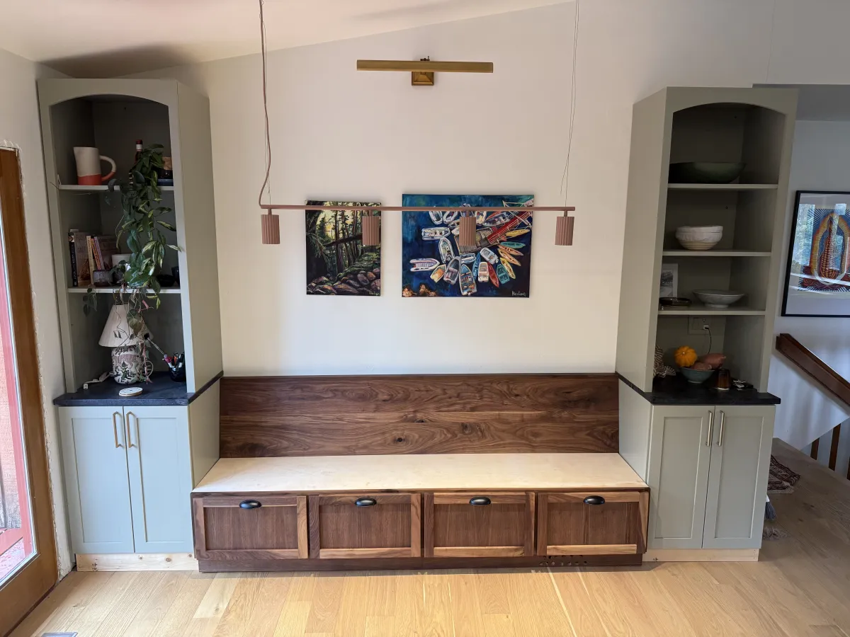 Built-in walnut entryway bench with sage green bookcase towers custom woodwork Alaska