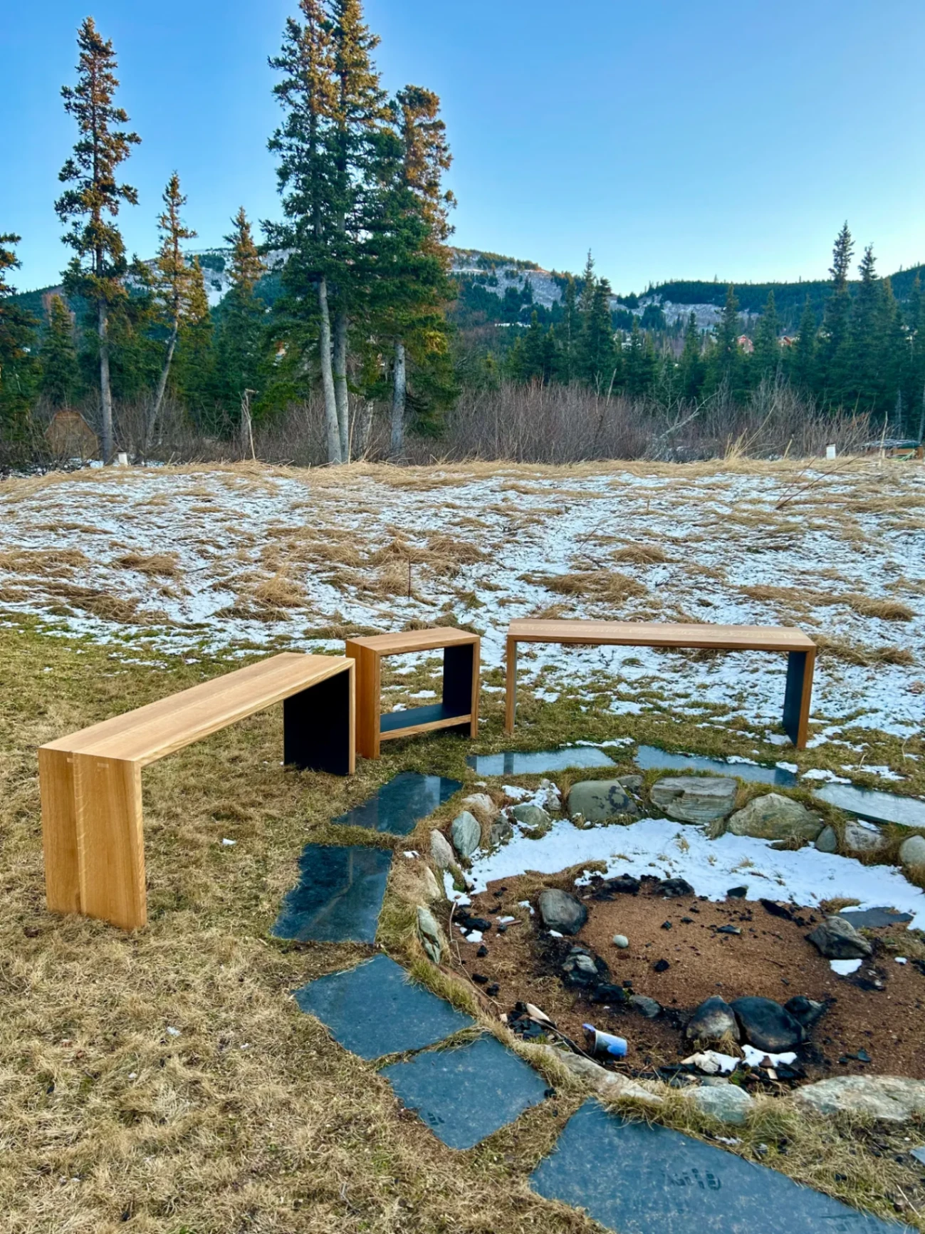 Handcrafted white oak waterfall benches around fire pit with Alaska mountains